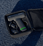 Hypervolt Go 3 massage device with green battery light in a black case on a textured blue surface