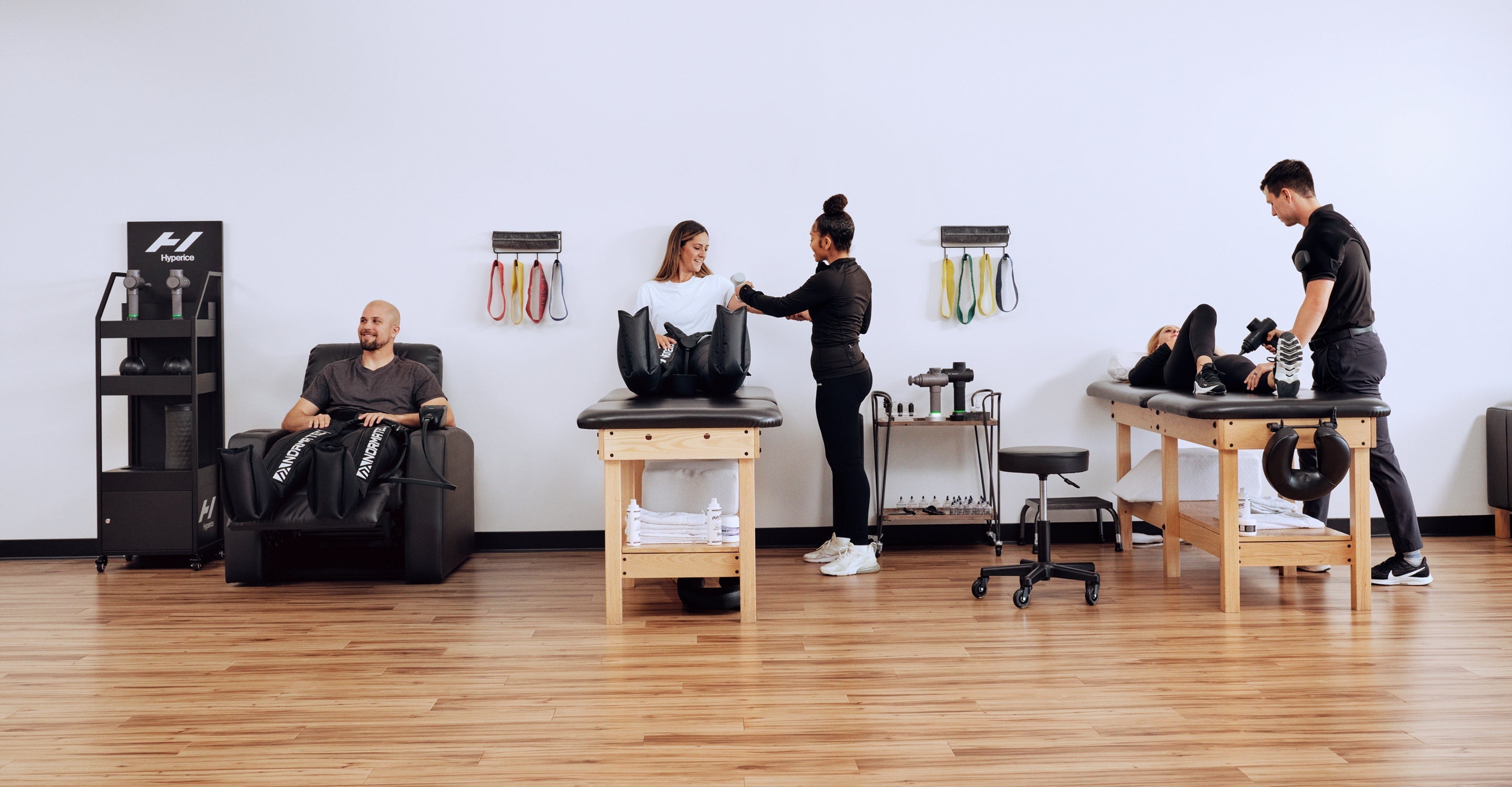 Physical therapy session with patients and therapists in a clinic setting using different Hyperice technology